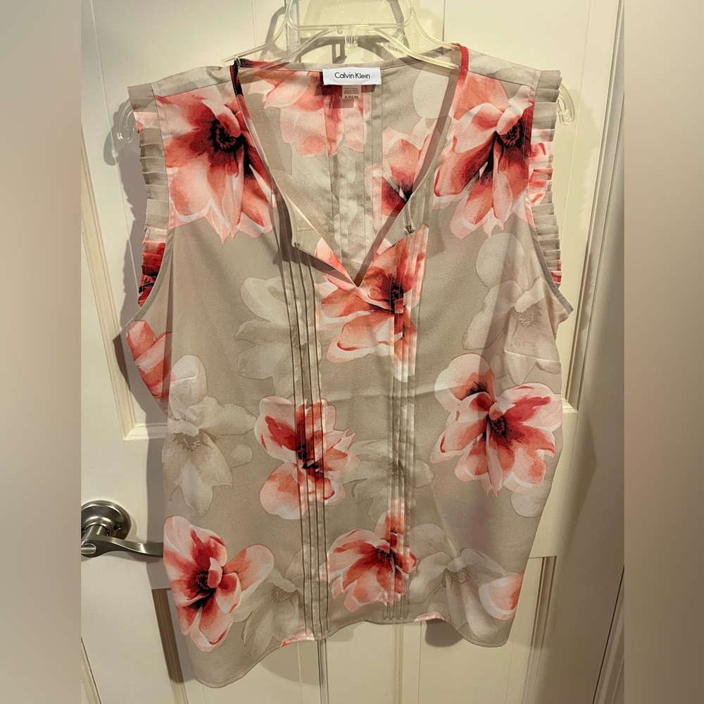Sleeveless tan top with pink flowers.